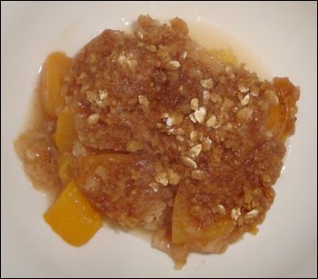 A portion of peach crisp that has been cooked in a crock pot and served in a bowl. Yum!