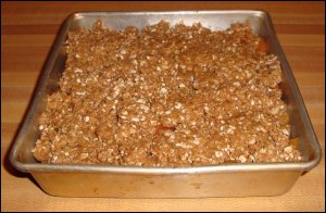 Oatmeal mixture on the top of the peaches in the completed peach crisp.