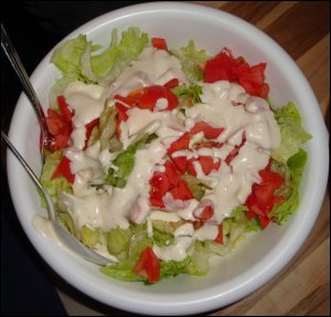 Salad with iceberg lettuce, tomato and salad dressing.