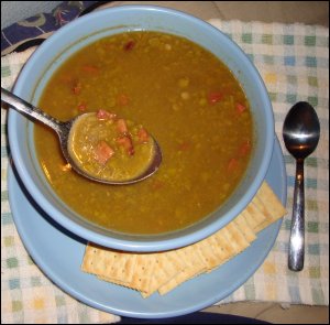 A bowl of split pea soup that had been warmed up in the microwave oven, with crackers on the side.