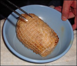 The cooked boneless turkey, still in its netting, in a bowl.