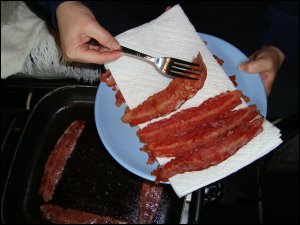 Placing the browned turkey bacon on paper towels.