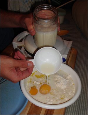 Mike measures milk into the bowl with the remaining waffle-making ingredients.