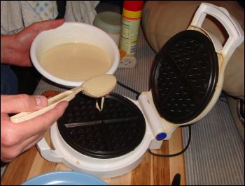 Mike places waffle batter into the waffle maker.