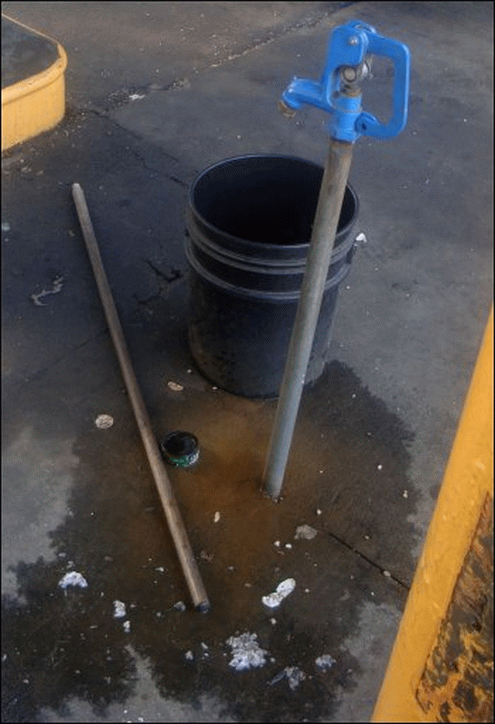 The dirty, oily, and ill-kempt area between fuel islands -- showing a bucket with no wash water for washing windshields, a pole without a squeegee on it, and trash on the ground -- at a fuel bay at the Pilot Travel Center in Dunn, NC, on Thursday, June 10, 2010.