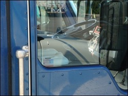 An ice chest sits in the passenger seat of a large truck. The driver keeps his cold food cold on ice.