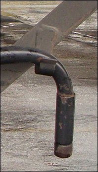 A close-up view of a landing gear crank handle, tucked into place behind a fixed hook on a trailer.