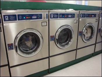 A row of triple load coin-operated washing machines that can be found in public laundromats.