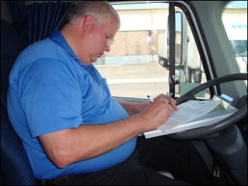 Mike Simons fills out a log sheet from a loose leaf log book.