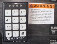 A Magtec keypad installed on a truck's dashboard, accompanied by a warning sticker.