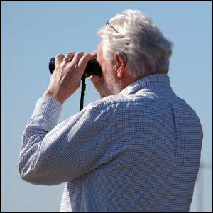 Man looking through binoculars, symbolizing searching.