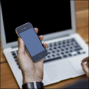 Man with cell phone and laptop computer, symbolizing the computer being tethered to the phone for access to the Internet.