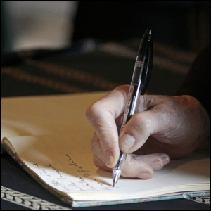 A man writing down information in a permanent book.