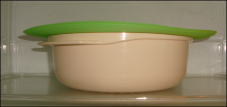 A lime green Micro Easy Grab serves as a splatter guard on top of a microwavable bowl with food inside.