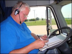 Professional truck driver Mike Simons uses both hands to use his cell phone, while wearing his hands-free Blueparrot Roadwarrior Bluetooth Noise Cancelling Headset.