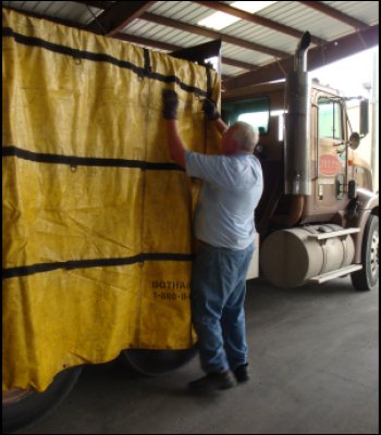 Professional truck driver Mike Simons is adjusting his tarp from the ground.