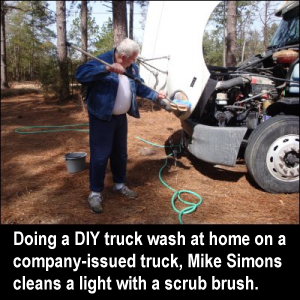 Doing a DIY truck wash at home on a company-issued truck, Mike Simons cleans a light with a scrub brush.