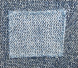 A close-up of the patch completely sewn on the jeans.