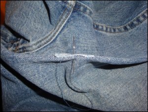 Holding the jeans and patch with preliminary stitches so that sewing on the edge can take place more easily.