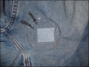 An embroidery hoop holds the jeans material taut for the preliminary stitches.