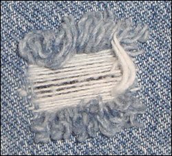 Close-up of original hole in jeans needing patching.