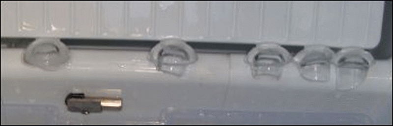 Very small ice caps in the portable ice maker resting on the divider between where the ice is made and stored.