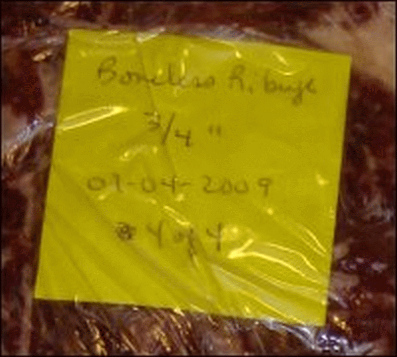 Label on a rib eye steak wrapped in plastic wrap and prepared for being put in the freezer.