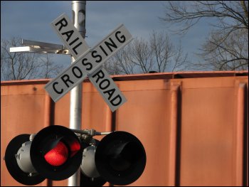 Railroad crossing sign with lights; container in background.