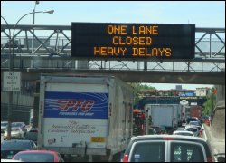 Road sign declaring a lane closure and heavy delay.