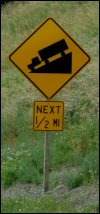 Road sign showing a down hill grade for trucks.