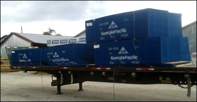 Damaged header board, broken bundle straps, broken load straps and shifted freight on flatbed trailer after close call with car that cut off truck.