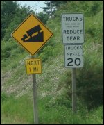 A road sign advising truck drivers of a one mile steep grade near Port Matilda Hill, this one instructing truck drivers to reduce gears for a maximum speed of 20 miles per hour.