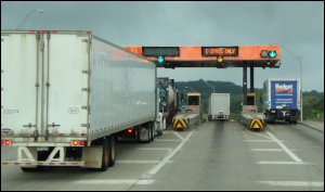 Notice one truck stopped behind another in a toll booth.