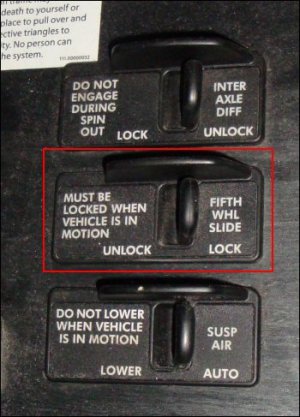 The fifth wheel slide lever is between two other levers on the dash of a Freightliner Columbia tractor.