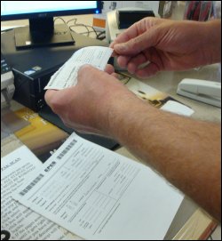 Mike peels off the backing of a TripPak Express adhesive label with load scanning confirmation.