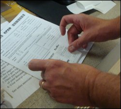 Once the backing is pulled away from the confirmation sticker, Mike applies it carefully to the bottom of the cover sheet.