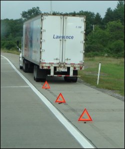 Truck on shoulder with emergency triangles placed behind.