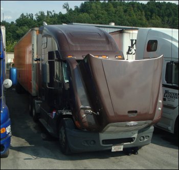 Truck parked at truck stop with hood up.