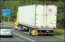 A truck parked on the side of the road in the emergency lane, breakdown lane or shoulder.