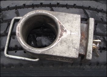 The Enforcer kingpin lock with key inserted in the lock -- and in an unlocked position -- sitting on top of a truck tire.