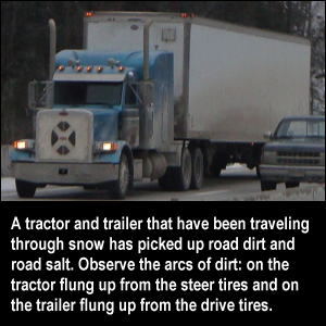 A tractor and trailer that have been traveling through snow has picked up road dirt and road salt. Observe the arcs of dirt: on the tractor flung up from the steer tires and on the trailer flung up from the drive tires.