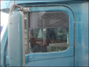 Truck window screen installed in a large truck: turquoise tractor.