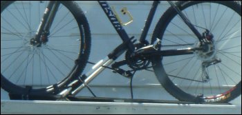 The trucker bike is tied down and braced on the rack.