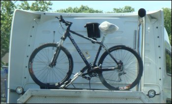 The trucker bike rests in a track on top of or behind the headache rack on the tractor.