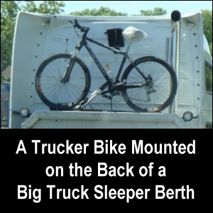 A trucker biken mounted on the back of a big truck sleeper berth.