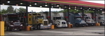 Large trucks getting fuel at a truck stop.