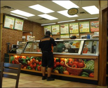 A professional driver for Schneider places an order at a Subway restaurant at a truck stop. If he has a driver rewards card, he can use his points toward his purchase.