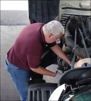 Mike checks out things under the truck's hood during an inspection.