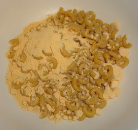 Uncooked Cheesy Mac in a bowl, before being added to bowling water.