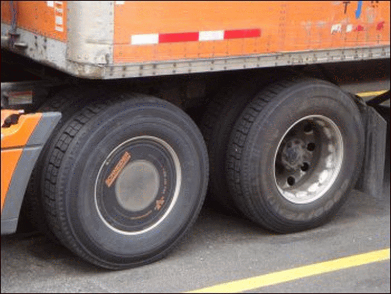 The drive tires on a Schneider tractor, one with a wheel cover and one without.